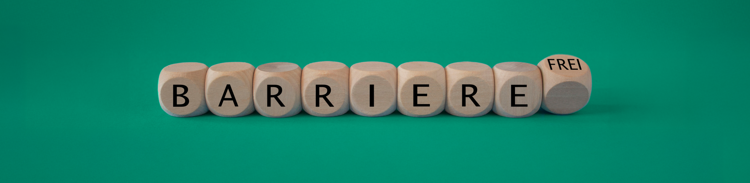 Barrierefreiheit Würfel die in einer Linie angeordnet sind und auf jedem steht ein einzelner Buchstabe die das Wort Barriere ergeben. Der letzte Würfel befindet sich im Fall und dort steht "frei" drauf.